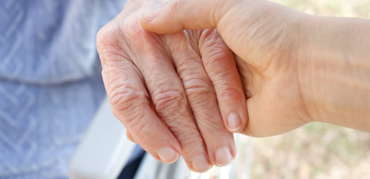 Eine jüngere Frau hält die Hand einer älteren Frau. Eine jüngere Frau hält die Hand einer älteren Frau.